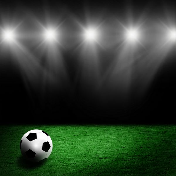 فوتبال روی چمن استادیوم با نور نورافکن ها می درخشید