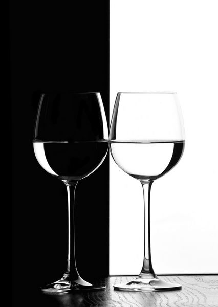 دو لیوان شراب با نور پس‌زمینه روی پس‌زمینه کنتراست سیاه و سفید