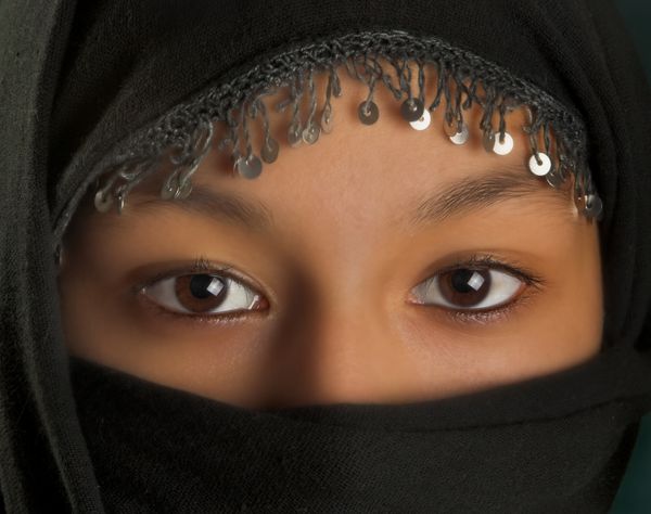 نمای نزدیک یک زن جوان اسلامی که با چادر مشکی پوشیده شده است