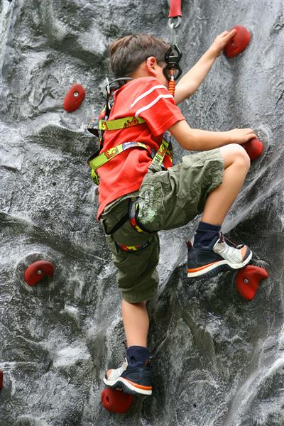 پسر جوانی که از دیوار صخره نوردی سرپوشیده بالا می رود