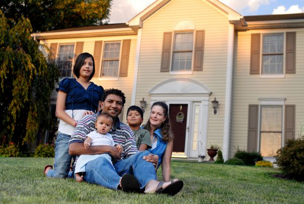 یک خانواده پنج نفره با نژاد مختلط با خانه حومه شهر پشت سرشان
