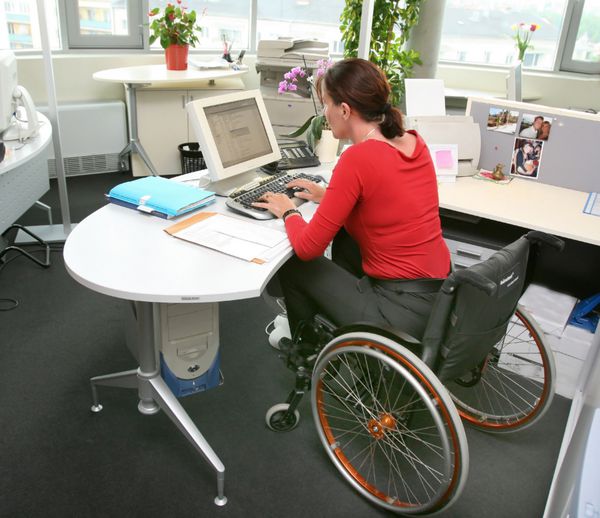 زن معلول روی ویلچر در دفتر کار روی کامپیوتر
