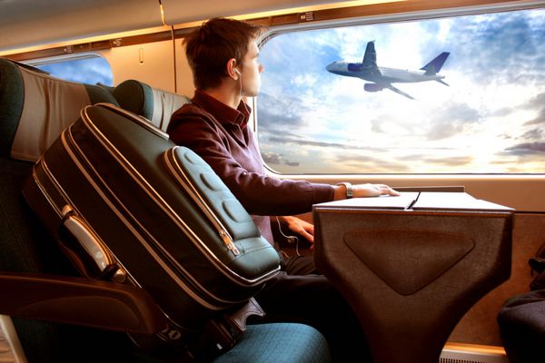 مردی در قطار که به غروب خورشید و هواپیما نگاه می کند