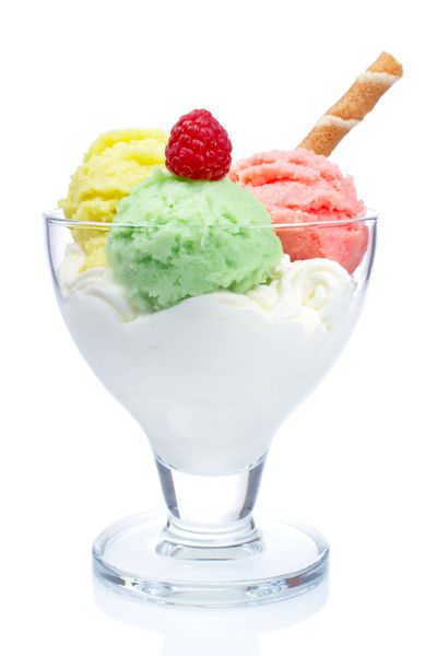 بستنی چند طعم خوشمزه در کاسه شیشه ای که در پس زمینه سفید منعکس شده است عمق میدان کم