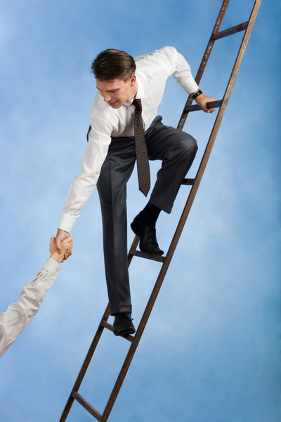 تصویر مفهومی از یک تاجر موفق که روی نردبان ایستاده و به شریک زندگی خود دست می دهد
