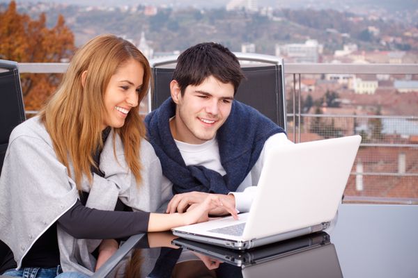 زوج جوان در حال گشت و گذار در اینترنت با لپ تاپ