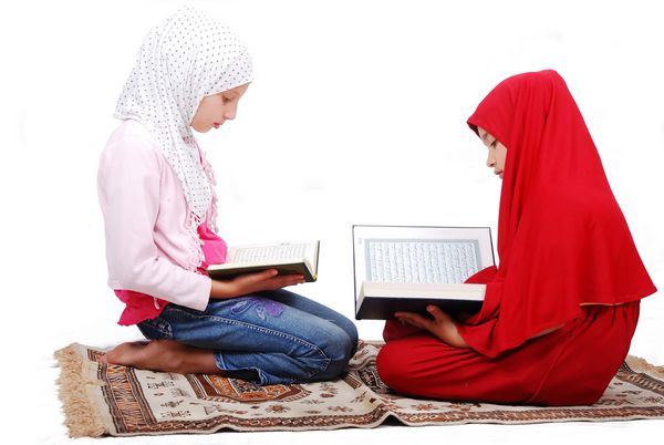 دختر جوان مسلمان با لباس سنتی در حال خواندن قرآن