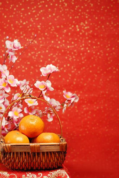 تزیین سال نو چینی--سبدی از پرتقال با گل آلو در زمینه جشن