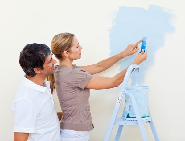 زوج خوشبخت در حال نقاشی با هم در خانه جدیدشان