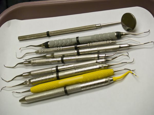 نه ابزار دندانپزشکی روی سینی قرار گرفته و آماده استفاده توسط دندانپزشک است