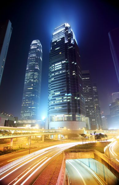 منطقه تجاری هنگ کنگ در شب ساختمان شرکت در عقب و ترافیک شلوغ در سراسر جاده اصلی در ساعت شلوغی