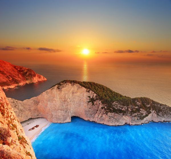 منظره ای از غروب خورشید بر فراز جزیره زاکینتوس یونان با یک کشتی غرق شده در ساحل شنی