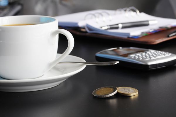 قهوه و سازمان دهنده در یک میز مشکی که استراحت یا صبحانه را در دفتر نشان می دهد