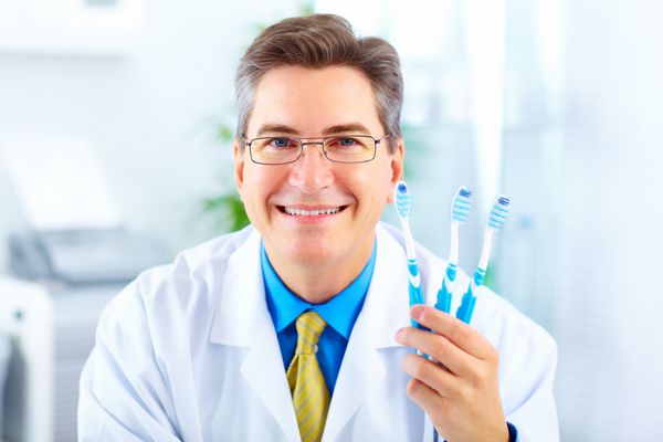 دندانپزشک خندان با مسواک در مطب