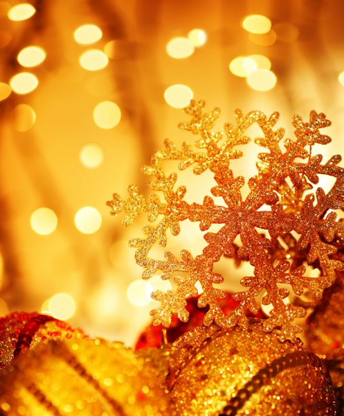 تزئینات طلایی درخت کریسمس و تزئینات تعطیلات با نورهای تاری دانه برف