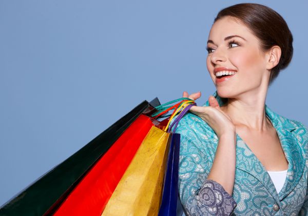 پرتره یک زن زیبا با کیسه های خرید رنگی جدا شده روی آبی