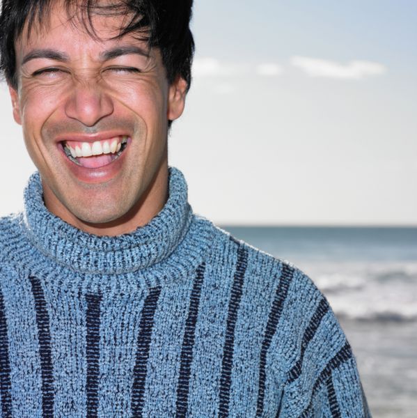 مرد جوانی که در ساحل لبخند می زند
