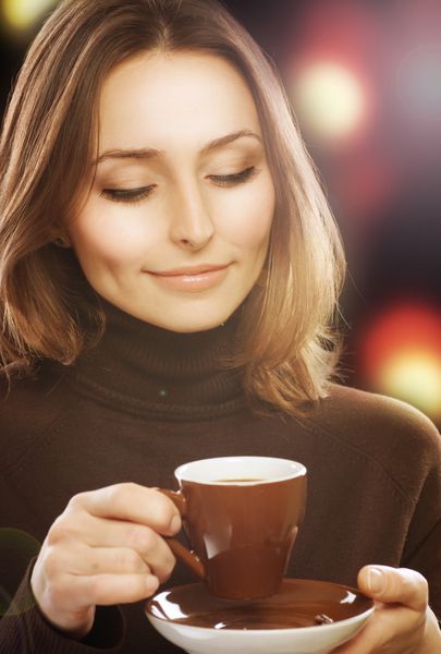 زن جوان زیبا در حال نوشیدن قهوه