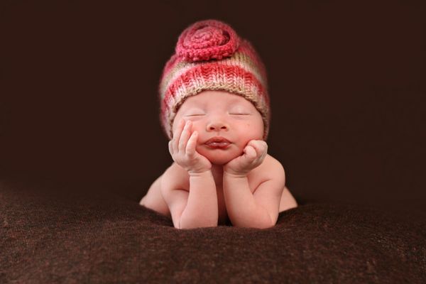 نوزاد زیبای تازه متولد شده دست هایش را روی صورتش گذاشته است