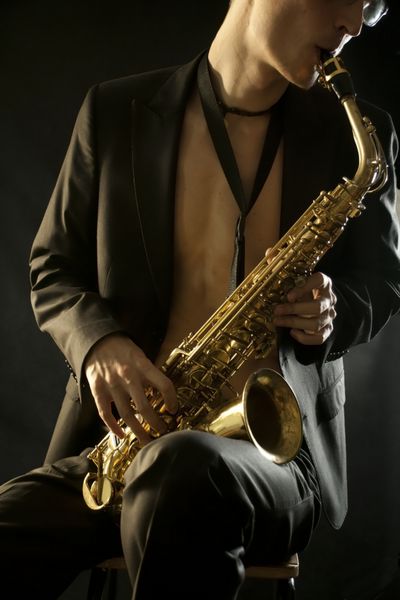 مرد جوان جاز در حال نواختن ساکسیفون روی مشکی