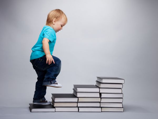 کودک نوپا در حال بالا رفتن از پله های ساخته شده از کتاب