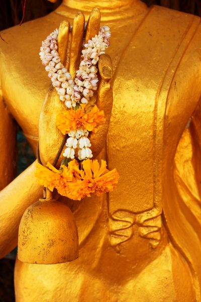 دست بودا حلقه های گل را در معبد تایلند قرار دهید