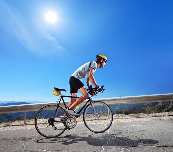 دوچرخه سوار در حال دوچرخه سواری در مقدونیه با خورشید در پس زمینه