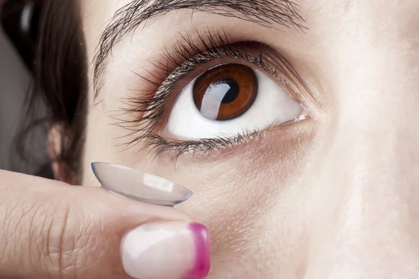 زنی که از لنز تماسی روی چشم خود استفاده می کند