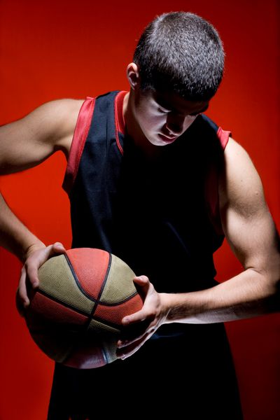 بازیکن بسکتبال که توپ را در پس زمینه قرمز جدا کرده است