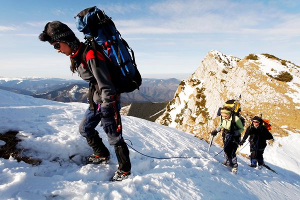 تیمی متشکل از سه کوهنورد در حال بالا رفتن از یک کوه