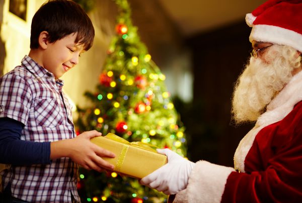 عکس پسر شاد در حال گرفتن هدیه از دستان بابا نوئل
