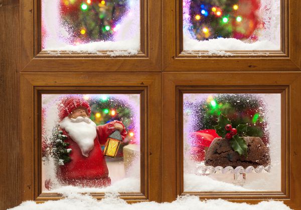پنجره ای برفی با پودینگ کریسمس و درختی با چراغ های پری چشمک زن