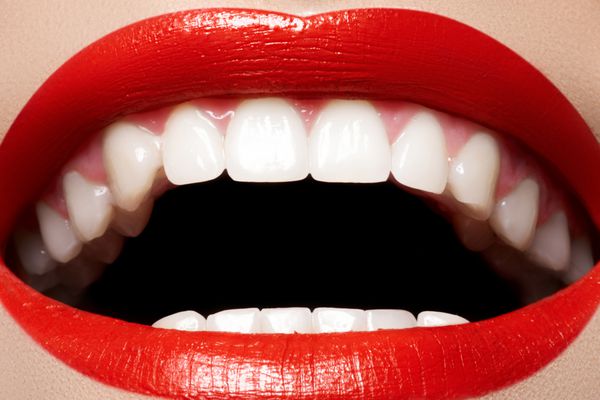 لبخند زنانه شاد از نمای نزدیک با دندان های سفید سالم آرایش لب های براق قرمز روشن زیبایی دندانپزشکی و مراقبت های زیبایی ماکرو دهان خندان زن