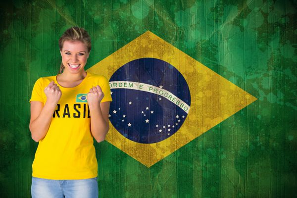 هوادار هیجان زده فوتبال با تی شرت برزیلی در برابر پرچم برزیل در جلوه گرانج