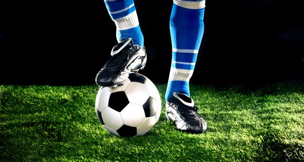 توپ فوتبال با پاهایش در زمین فوتبال