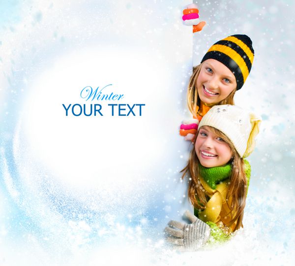 دختران نوجوان زمستانی که از پشت تابلوی بیلبورد خالی نگاه می کنند فضایی برای متن شما فروش