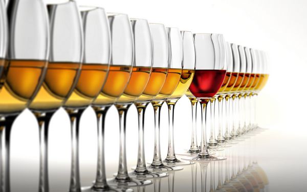 ردیفی از چندین لیوان شراب سفید با یک لیوان قرمز در وسط روی یک سطح بازتابنده سفید و پس زمینه سفید