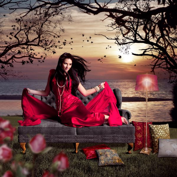 زن زیبا با لباس شب روی مبل قدیمی کنار دریاچه نشسته است