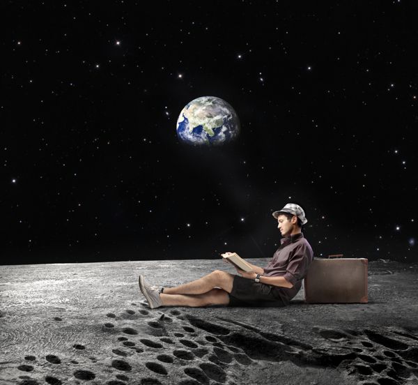 مرد جوانی روی ماه نشسته و در حال خواندن کتابی با زمین در پس‌زمینه است عناصر این تصویر توسط ناسا ارائه شده است