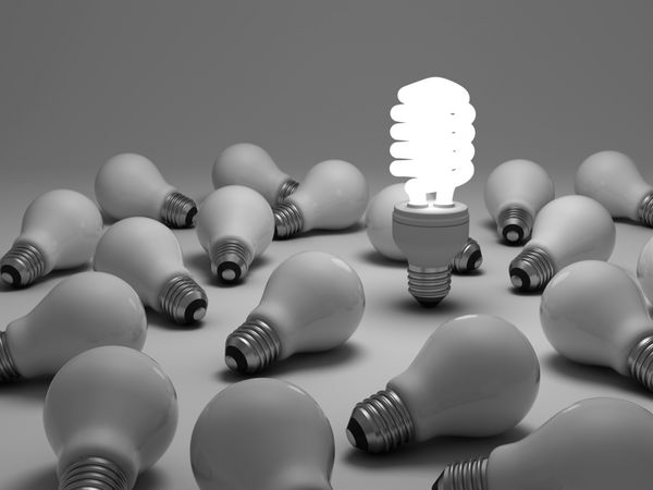 مفهوم لامپ صرفه جویی در مصرف انرژی یک لامپ فلورسنت فشرده و درخشان در میان لامپ های رشته ای بدون روشنایی در پس زمینه سفید