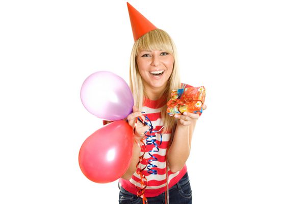 زن جوان زیبا در حال جشن تولد در یک دست و توپ های دیگر در جعبه هدیه کلاه کاغذی جدا شده بر روی پس زمینه سفید