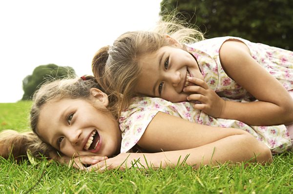 دو خواهر در حال خندیدن و بازی در پارک دراز کشیدن
