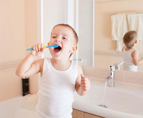 پسر در حال تمیز کردن دندان در حمام