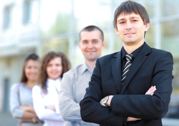 تیم تجاری در یک ردیف در دفتر ایستاده و به دوربین نگاه می کند - تیم تجاری موفق