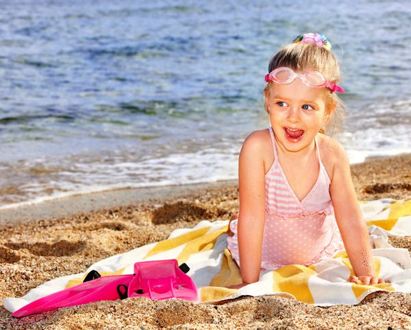 دختر کوچکی که در ساحل بازی می کند