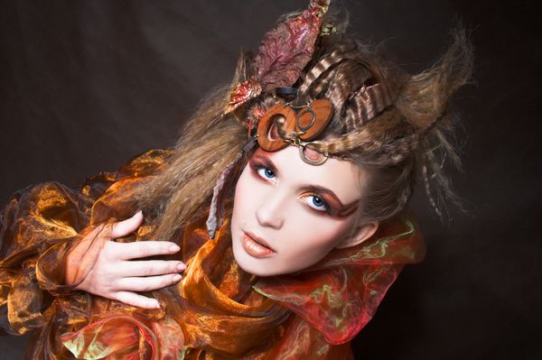 فصل پاييز زن جوان با چهره و مدل موی هنرمندانه و با برگ های خشک در موهایش