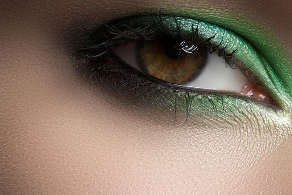 نمای نزدیک ظرافت چشم زن با سایه چشم دودی سبز عکس ماکرو از قسمت صورت
