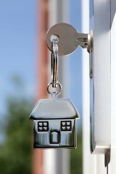 کلید خانه روی جاکلیدی نقره ای شکل خانه در قفل در