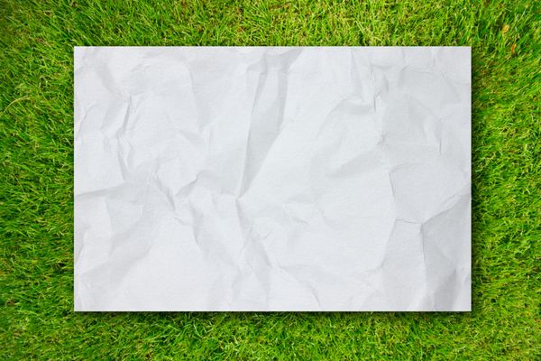 کاغذ مچاله شده سفید در زمینه چمن سبز