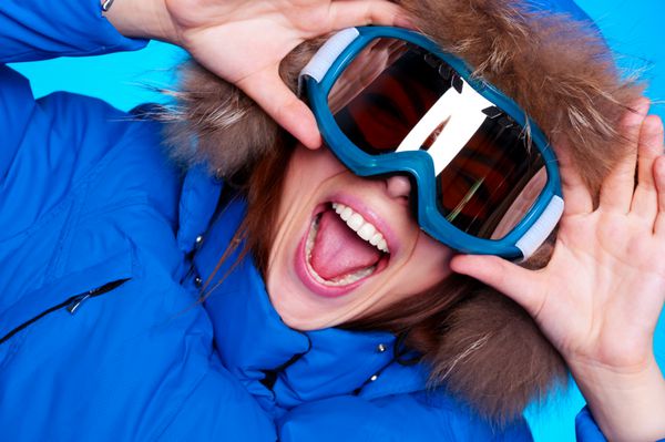 زن احساسی شاد با عینک اسکی و کت زمستانی